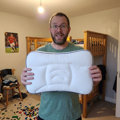 A father standing in his child's bedroom, holding up the Hushly Kids pillow.