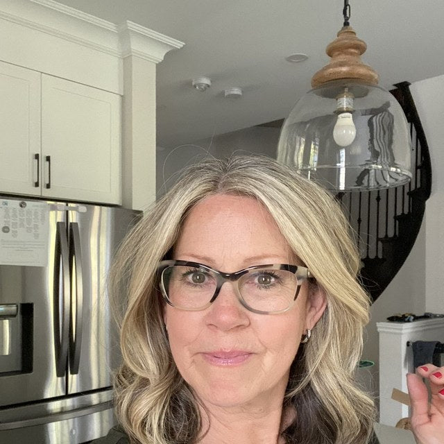 Reviewer photo: a woman wearing glasses, standing in her kitchen