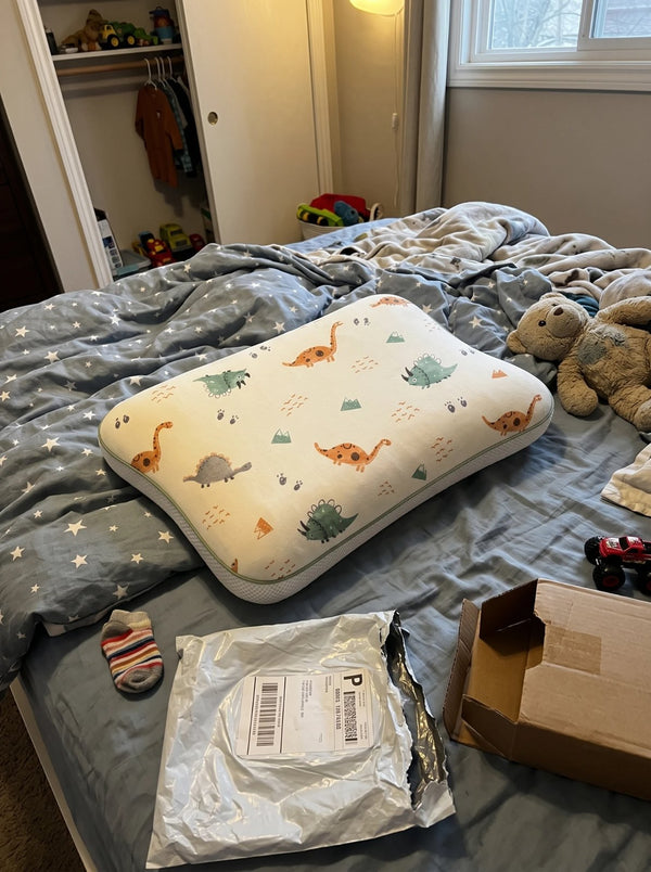 The Hushly Kids pillow in its Dino pillowcase, just unpacked on the bed