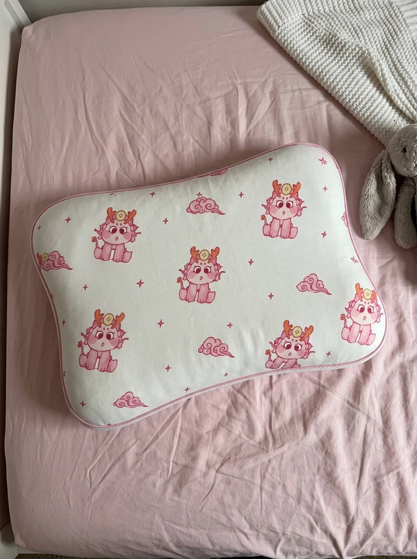 The Hushly Kids pillow in its Fairy Dragon pillowcase on a pink sheet