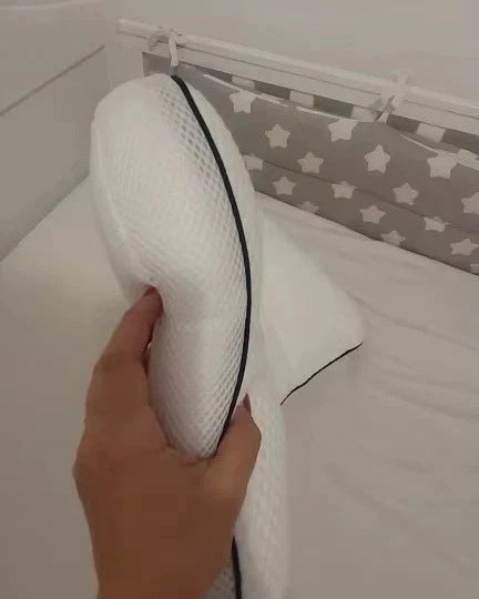 Parent holding the pillow on its side by the cot, showing the low profile