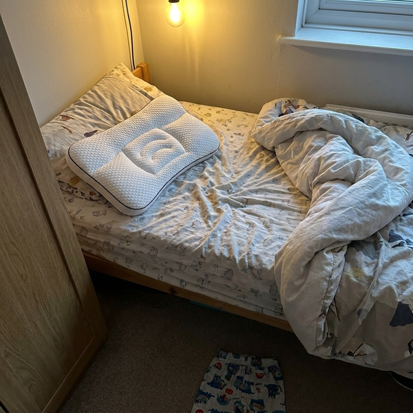 Hushly Kids pillow on a child's unmade bed in the evening light