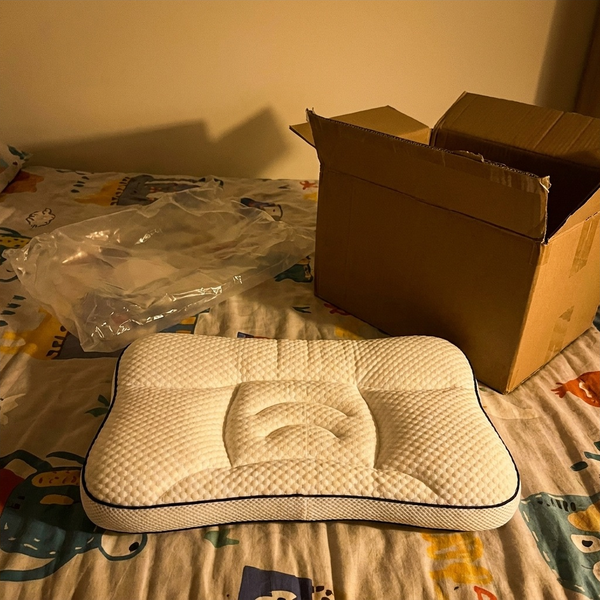 Hushly Kids pillow just unpacked on a child's bed, the delivery box behind it