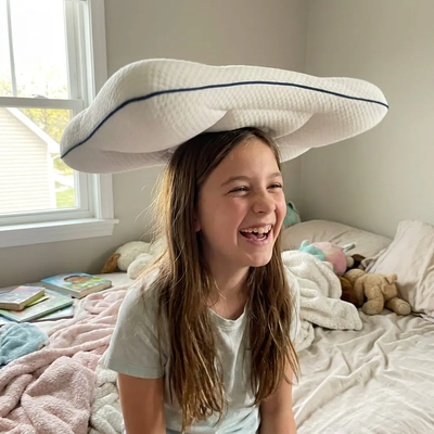A girl laughing with the Hushly Kids pillow balanced on her head.